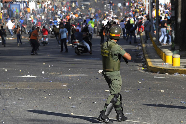 Armed military man pointing gun at demonstrants