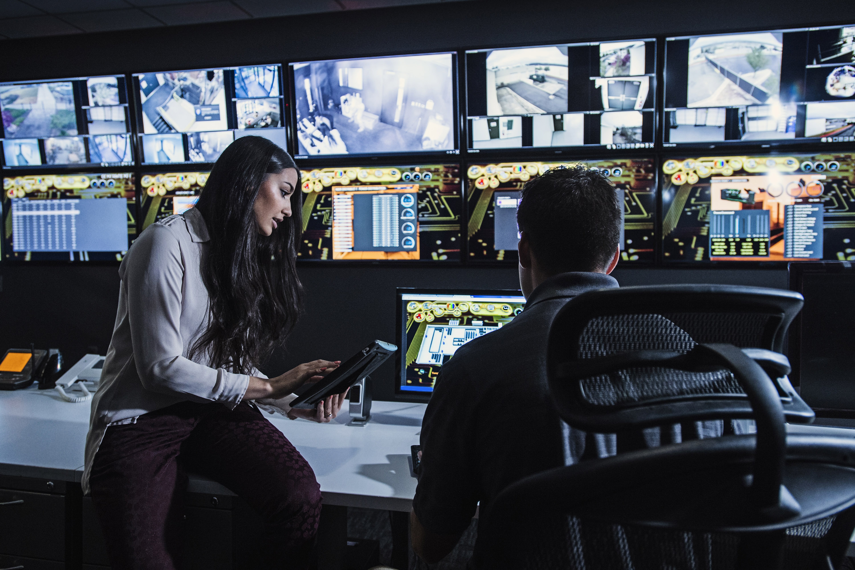 A lady and a gentleman woking on a cybersecurity emergency in front of multiple computers.