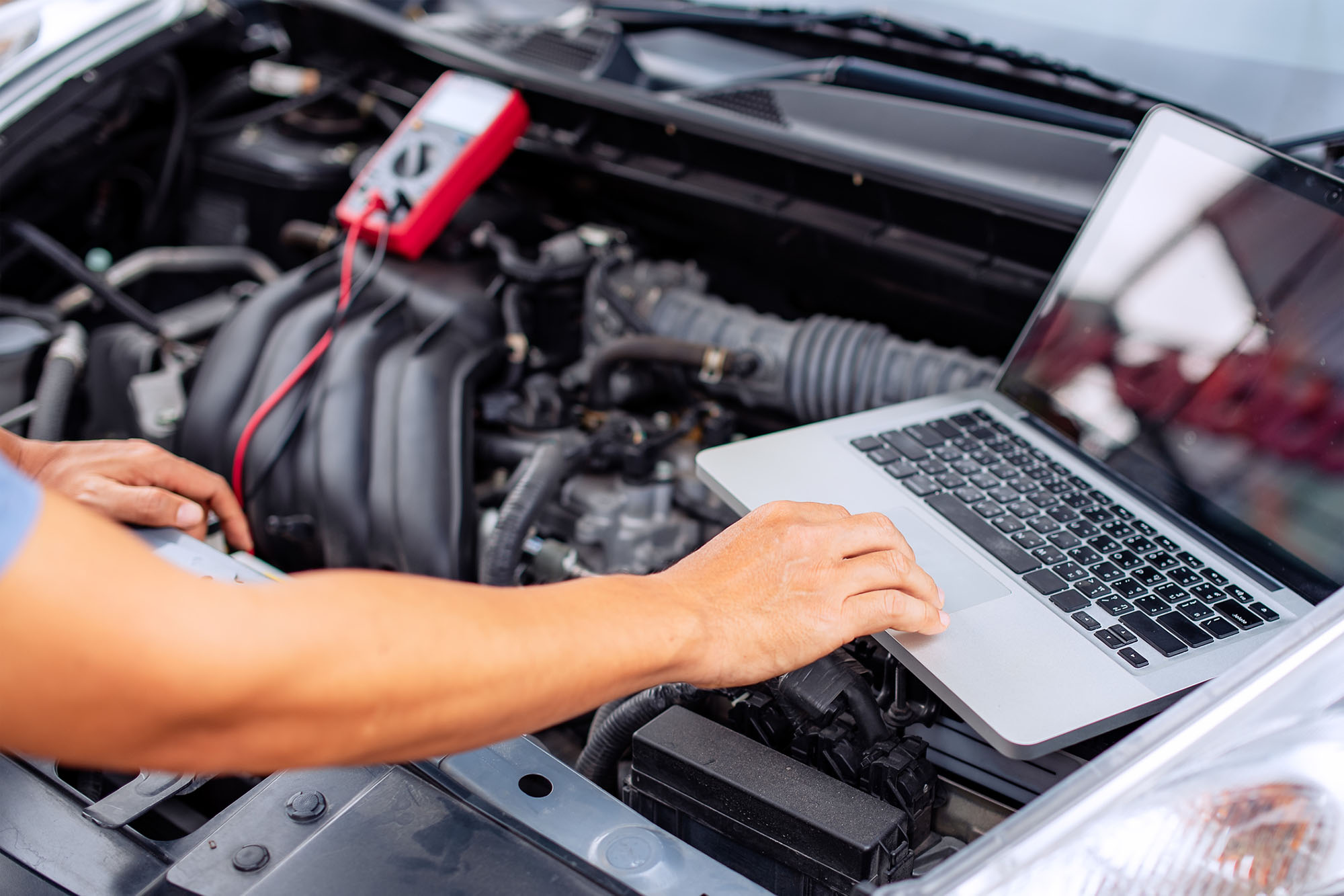 Meccanico uomo che utilizza il computer portatile esaminando la messa a punto di fissaggio riparazione auto