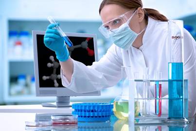 A female scientist checking a blue liquid in test tube in a laboratory.  