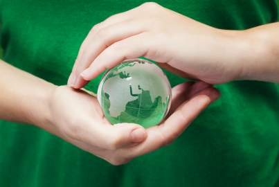 A person holds a glass globe in front of their green t-shirt