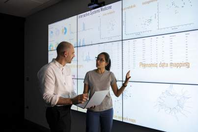 A lady showing her colleague a big screen of data. 