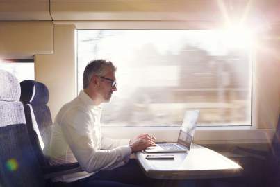 Man sitting on a train working on a laptop